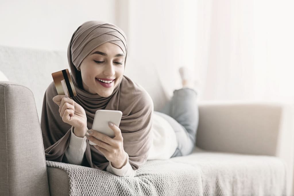 A woman in a hijab shopping on her phone at home